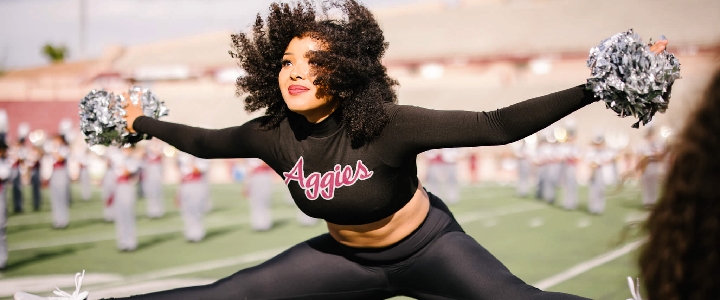 An NMSU Cheerleader does a standing splits move.